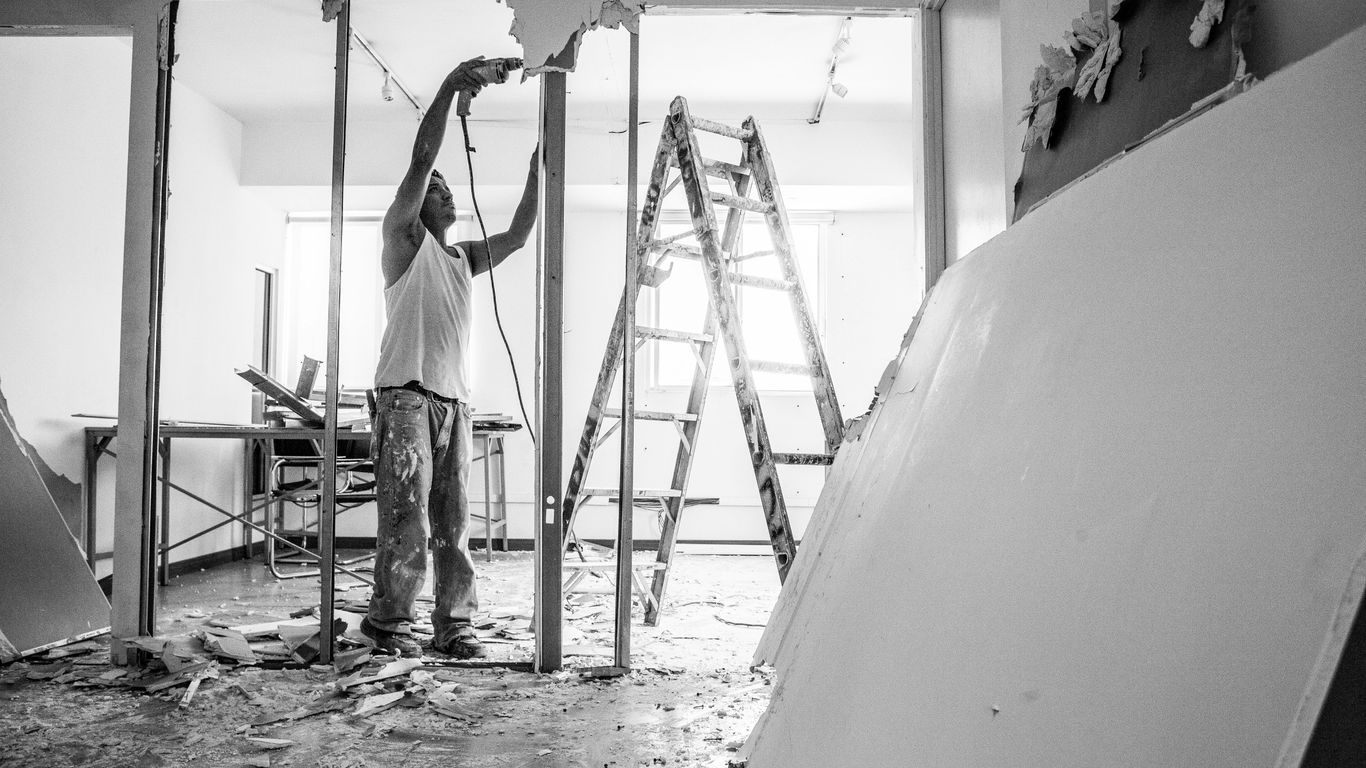 man in white t-shirt and black pants standing on ladder
