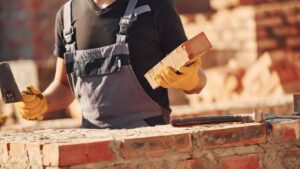 A person is building a brick wall with a trowel and bricks.