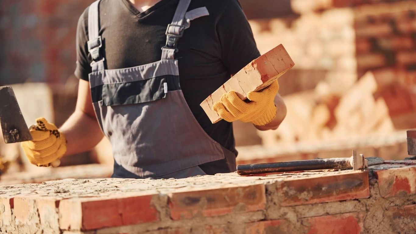 A person is building a brick wall with a trowel and bricks.