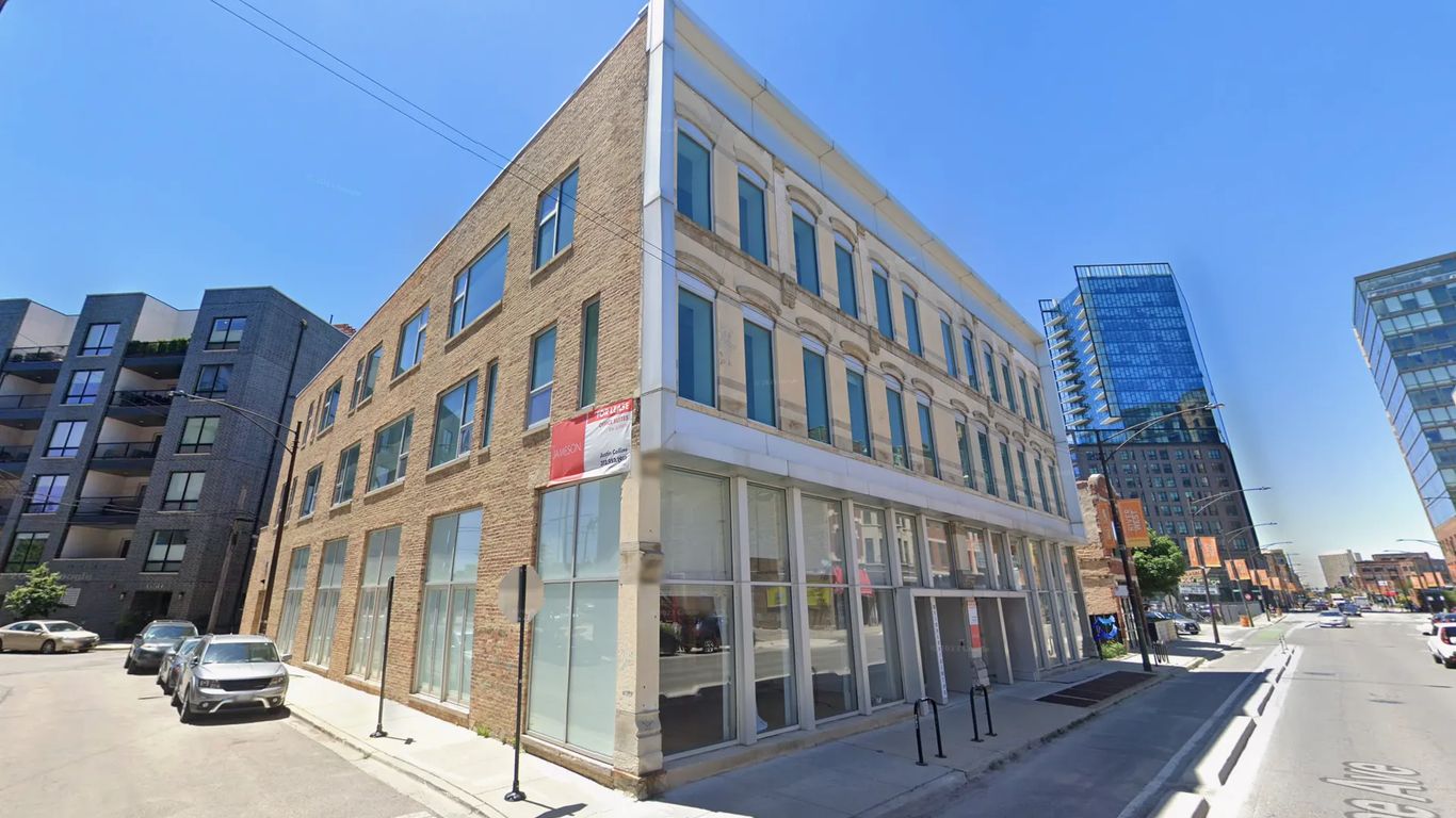 Corner building with brick facade and modern additions on a sunny day.