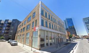 Corner building with brick facade and modern additions on a sunny day signifying expert masonry work.