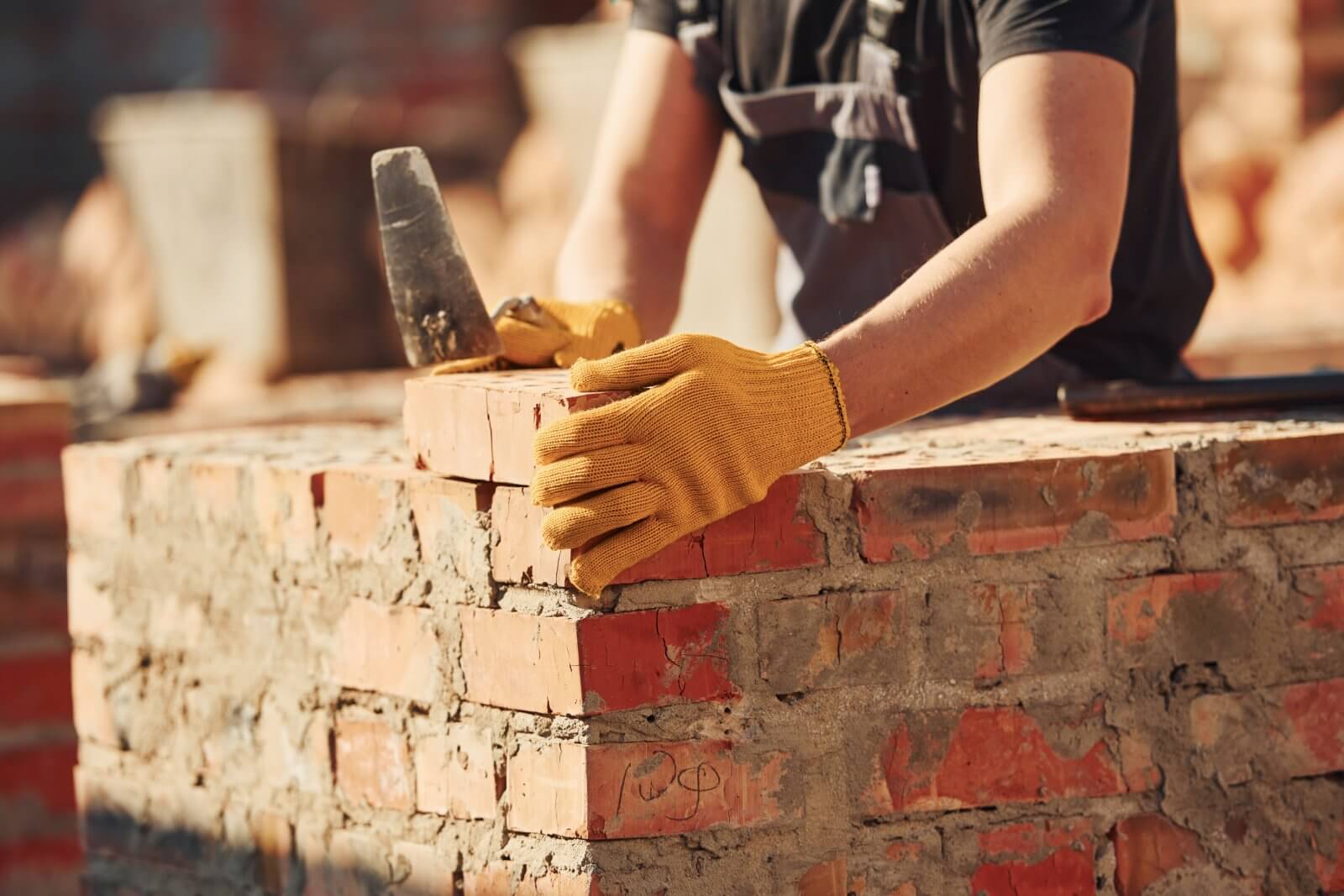 A professional mason carefully placing bricks during a tuckpointing repair project.