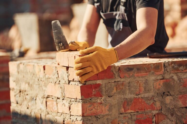 A professional mason carefully places a brick on a wall during repair.